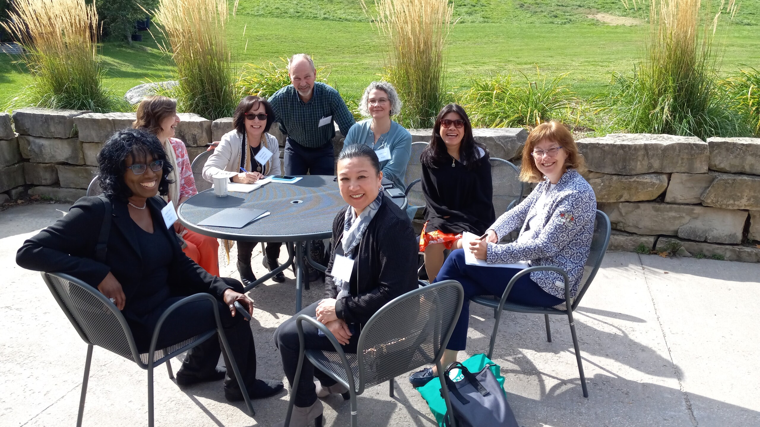 several board members sitting around a table outdoors in the sun in the middle of meeting